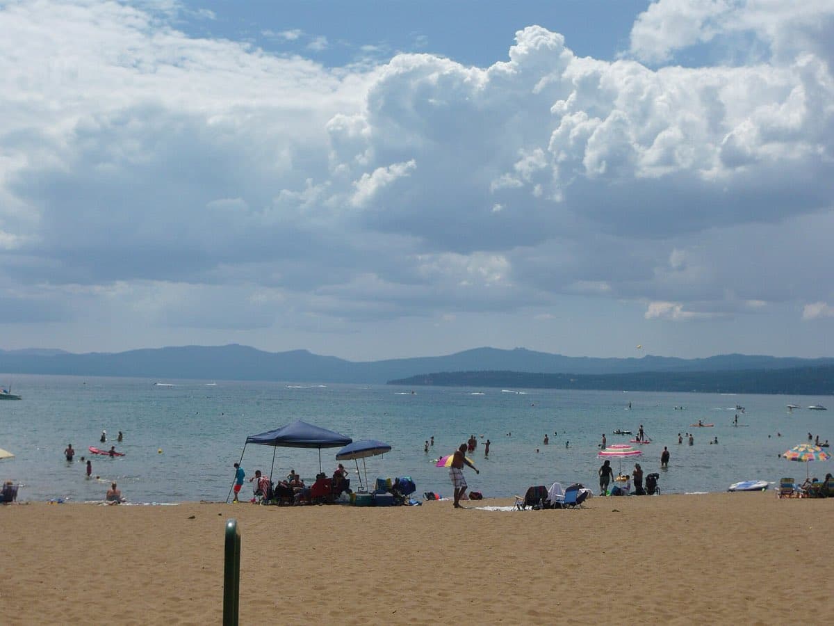 Swimmers and sunshades on the sand at Kings Beach State Recreation Area on Lake Tahoe