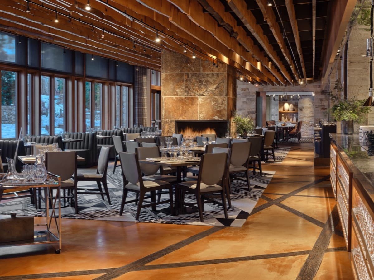 The Manzanita dining room at The Ritz-Carlton, Lake Tahoe, with its stone fireplace and mountain-view windows